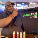 Former NFL athlete holding painzen lotion shirt expressing pride in the lotion and how well it works even for those suffering from years of chronic pain on homepate